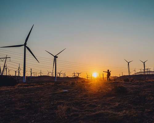 motor silhouette photography of person standing near windmill machine